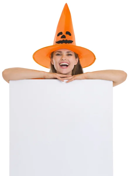 Mulher sorridente em chapéu de Halloween com cartaz em branco — Fotografia de Stock