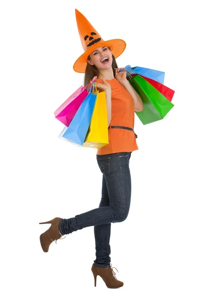 Mujer joven sonriente en sombrero de Halloween con bolsas de compras —  Fotos de Stock