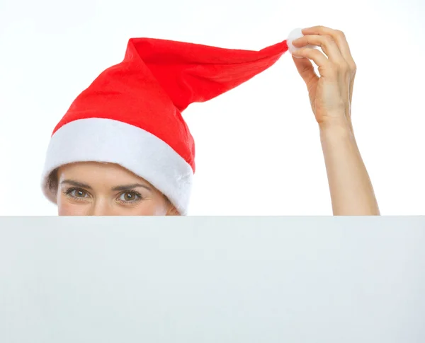 Closeup on female head in Christmas hat hiding behind blank bill — Stock Photo, Image