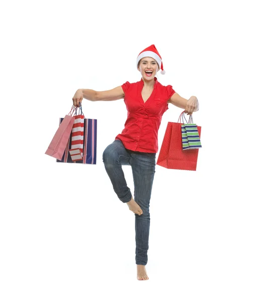 Smiling young woman in Santa hat dancing with shopping bags — Stock Photo, Image