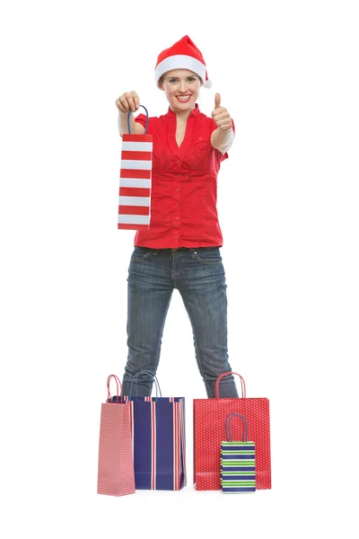Счастливая молодая женщина в рождественской шляпе стоит среди сумки — стоковое фото