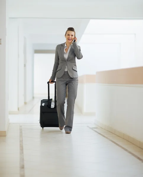 Affärskvinna i business trip promenader med hjul väska och tala — Stockfoto