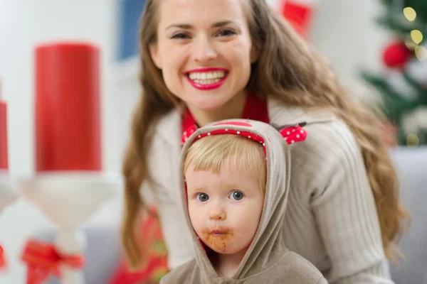 Porträt einer lächelnden jungen Mutter und eines verschmierten Babys an Weihnachten — Stockfoto