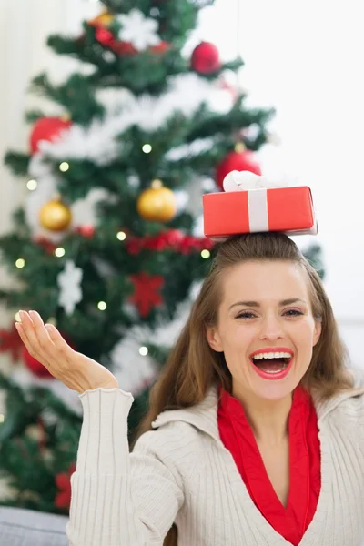 Glückliche junge Frau balanciert Weihnachtsgeschenkschachtel auf Kopf — Stockfoto