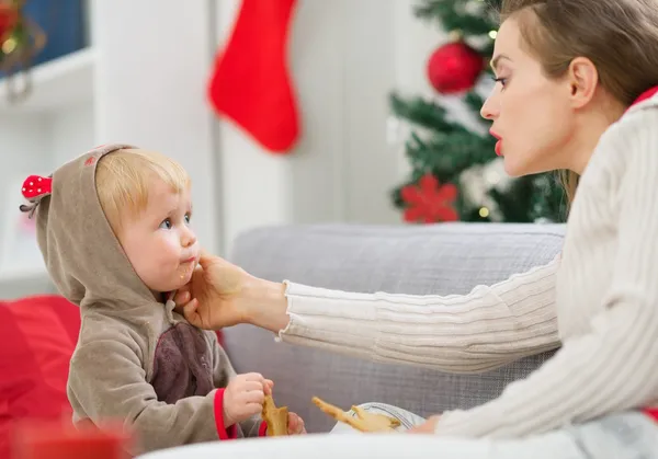 Madre limpieza comer manchado bebé comer galletas de Navidad — Foto de Stock