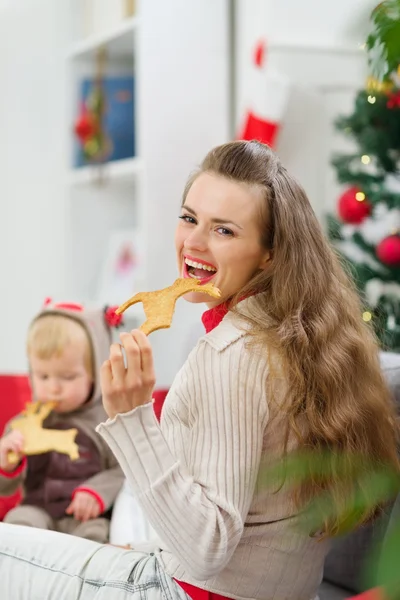 Mor och barn äta christmas rådjur formad kakor — Stockfoto