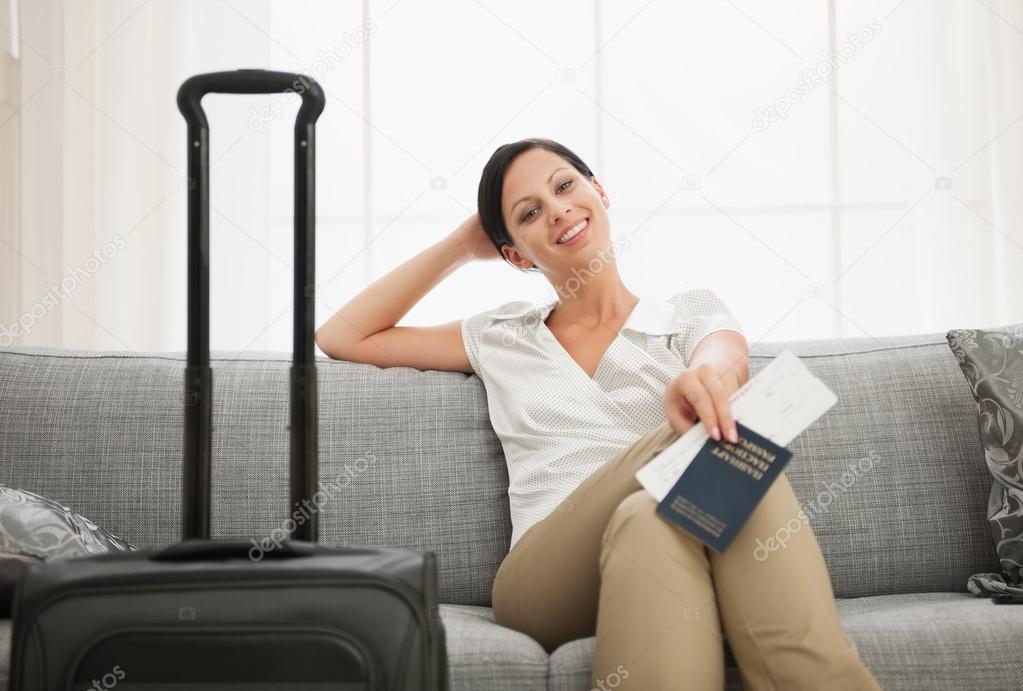 Smiling young woman with bag holding passport and air ticket