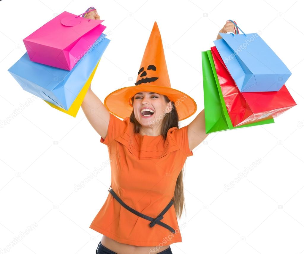 Smiling woman in Halloween hat rising up shopping bags