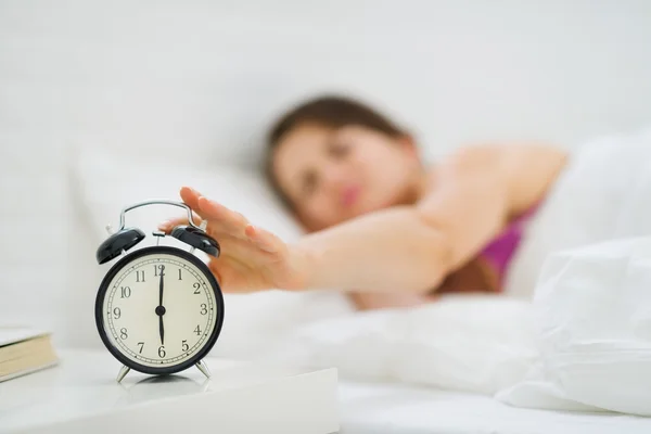 Closeup on woman hand reaching to turn off alarm clock — Stock Photo, Image