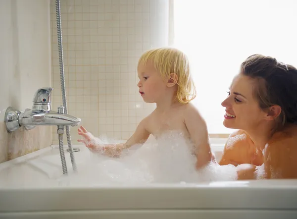 Moeder en baby spelen in badkuip — Stockfoto