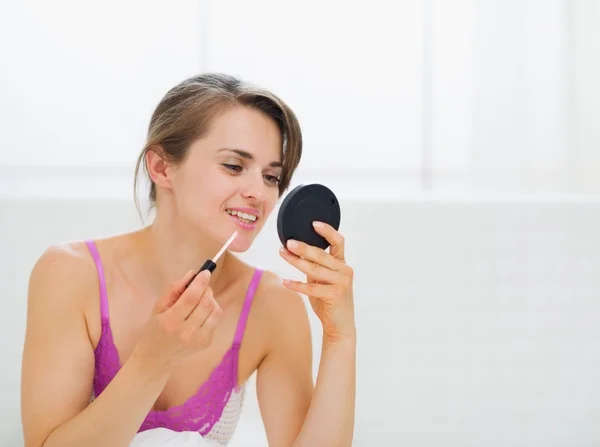 Girl sitting in bed and applying makeup — Stock Photo, Image