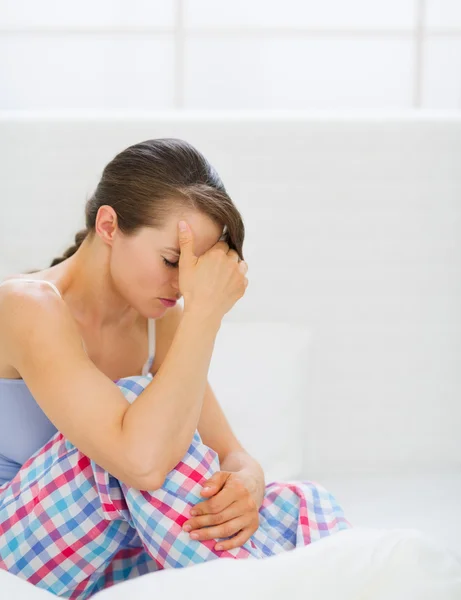 Stressed young woman sitting on bed — Stock Photo, Image