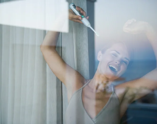 Young woman with electric toothbrush stretching after sleep — Stock Photo, Image