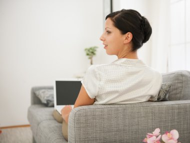 kanepede döşenmesi ve dizüstü bilgisayar üzerinde çalışan bir kadın. arka görünüm