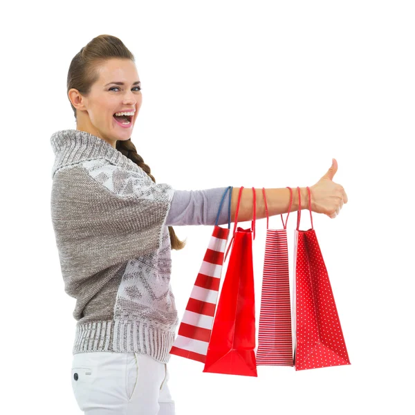 Mujer feliz en suéter mostrando los pulgares hacia arriba con bolsas de compras —  Fotos de Stock