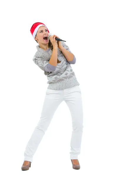 Felice donna a Babbo Natale cappello cantare in microfono e guardando co — Foto Stock