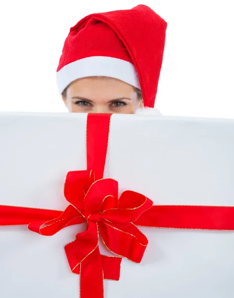 Kvinna i santa hatt gömmer sig bakom stora julklapp — Stockfoto