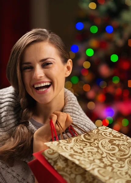 Mujer sonriente con bolsa de compras frente a las luces de Navidad —  Fotos de Stock