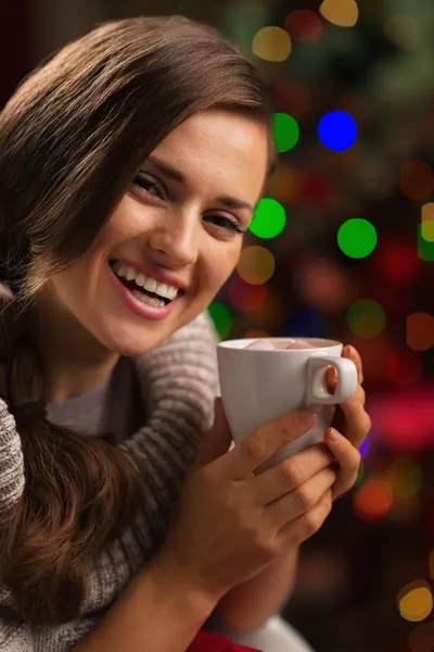 Happy young woman enjoying cup of hot chocolate in front of Chri — Stock Photo, Image