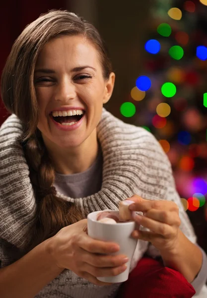 Glückliche junge Frau nimmt Marshmallow aus einer Tasse heißer Schokolade — Stockfoto