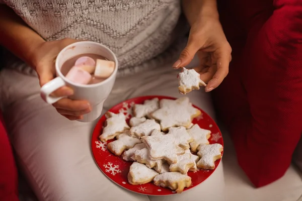 Primer plano de la mujer comiendo galletas de Navidad y bebiendo chocol caliente — Foto de Stock