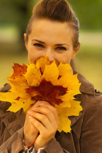 Happy woman hiding behind bunch of fallen leaves — Stock Photo, Image