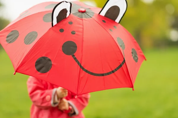 Baby hiding behind red umbrella — Stock Photo, Image