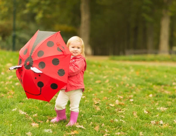 Açık havada kırmızı şemsiye ile oynarken mutlu bebek — Stok fotoğraf