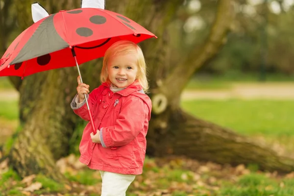 Açık havada kırmızı şemsiye ile gülümseyen bebek portresi — Stok fotoğraf