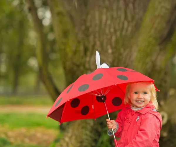 Portret szczęśliwy dziecka z czerwony parasol na zewnątrz — Zdjęcie stockowe