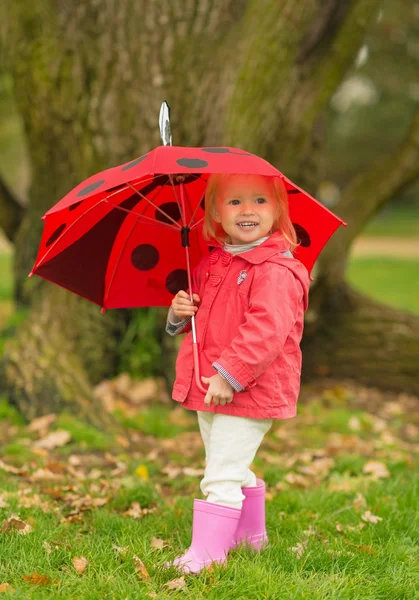 Volledige lengte portret van gelukkig baby met rode paraplu buitenshuis — Stockfoto