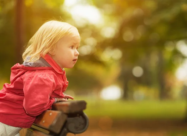 Baby lener seg mot benken og ser på kopirom – stockfoto