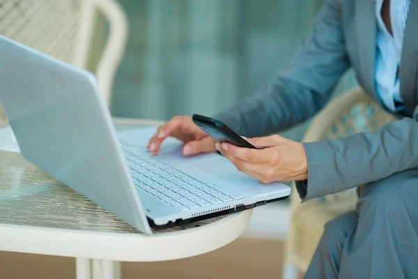 Primo piano sulla donna d'affari che lavora sul computer portatile e tenendo mobile p — Foto Stock