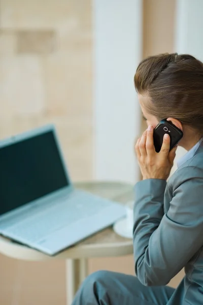 ビジネスの女性話す携帯電話とノート パソコンで見ています。後部 v — ストック写真