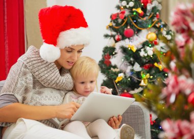 Anne ve bebek kız Noel ağacının yakınında Tablet PC'yi kullanma