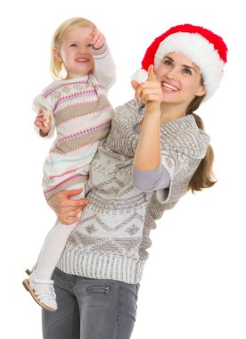 Polis üzerinde yukarıyı Noel şapka ve bebek kız annesi gülümseyerek