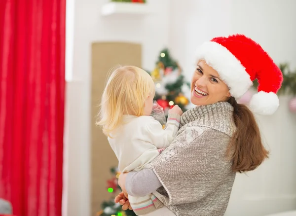 Mutter hält Baby vor Weihnachtsbaum — Stockfoto