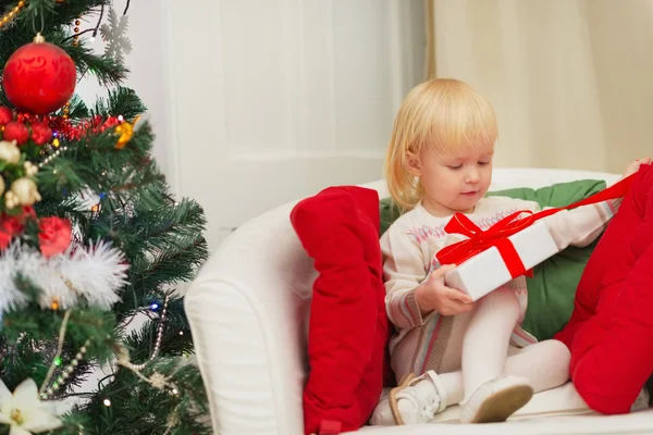 Bebê sentado na cadeira e abrir a caixa de presente de Natal — Fotografia de Stock