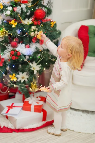 Verschmutztes Baby isst Weihnachtsplätzchen in der Nähe des Weihnachtsbaums — Stockfoto