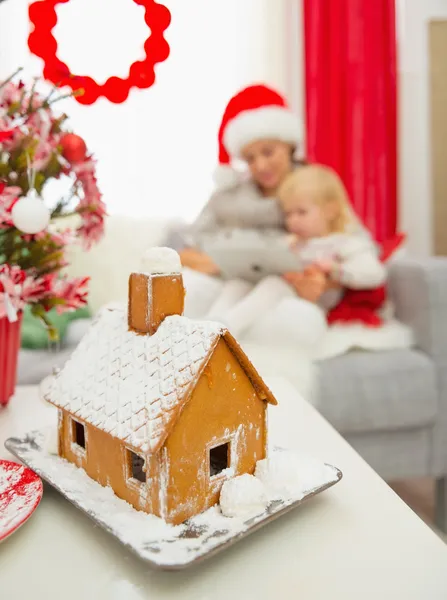 Fechar na casa de pão de gengibre de Natal e mãe e bebê usando — Fotografia de Stock