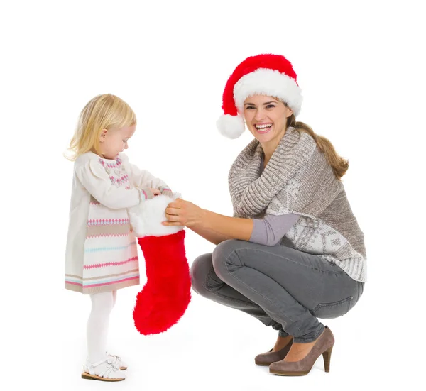 Mãe feliz segurando meia de Natal enquanto bebê menina tirando p — Fotografia de Stock