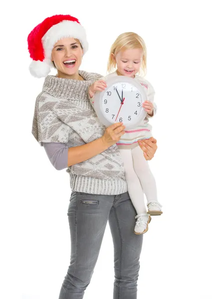 Mãe feliz no chapéu de Natal e bebê menina segurando relógio — Fotografia de Stock