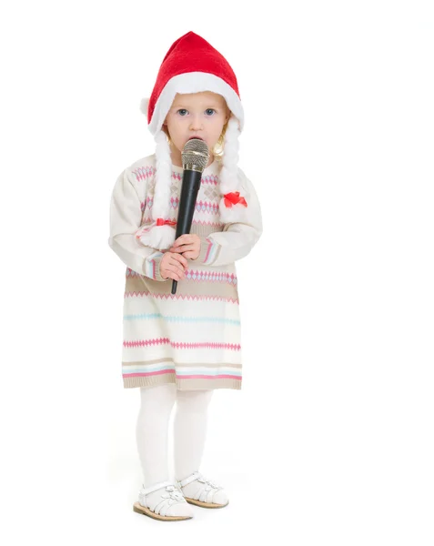 Holčička v klobouku vánoční pomocí mikrofonu — Stock fotografie