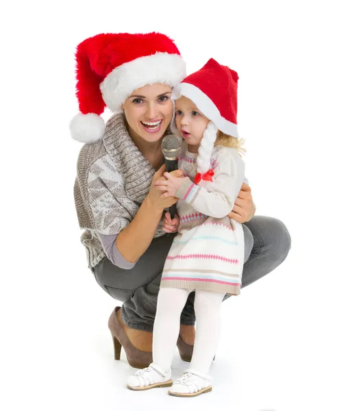 Weihnachtsporträt einer glücklichen Mutter und eines kleinen Mädchens, die in mi singen — Stockfoto