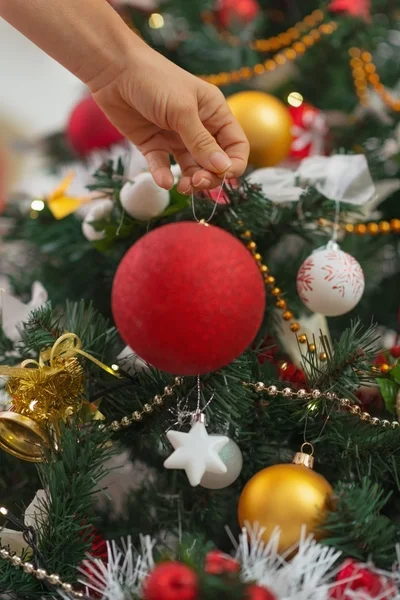 Primer plano en la mano de la mujer colgando la bola de Navidad en el árbol de Navidad — Foto de Stock