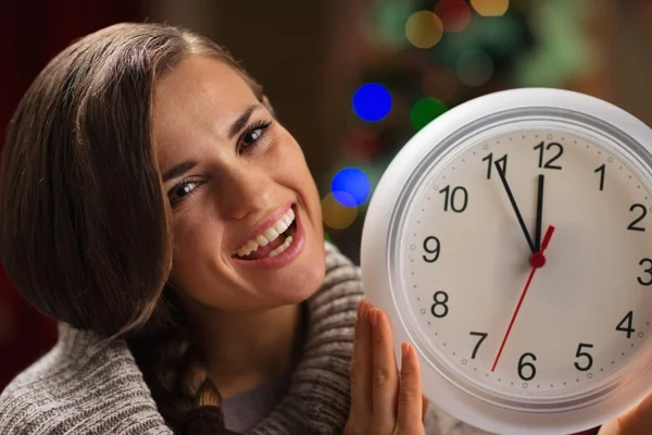 Portrait of smiling young woman showing clock in front of Christ — Stock Photo, Image