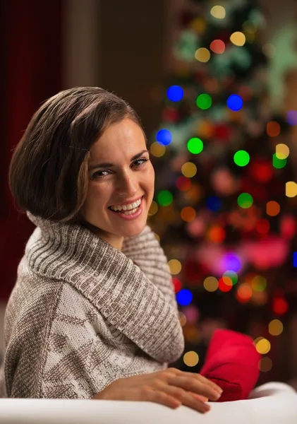 Gelukkig jonge vrouw zit kerstboom — Stockfoto