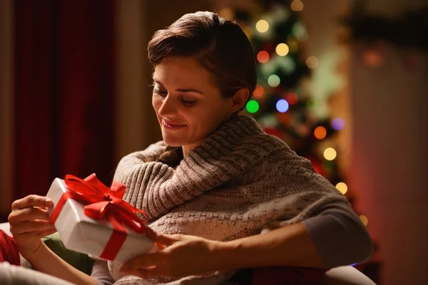 Glückliche junge Frau sitzt Stuhl mit Weihnachtsgeschenkschachtel — Stockfoto