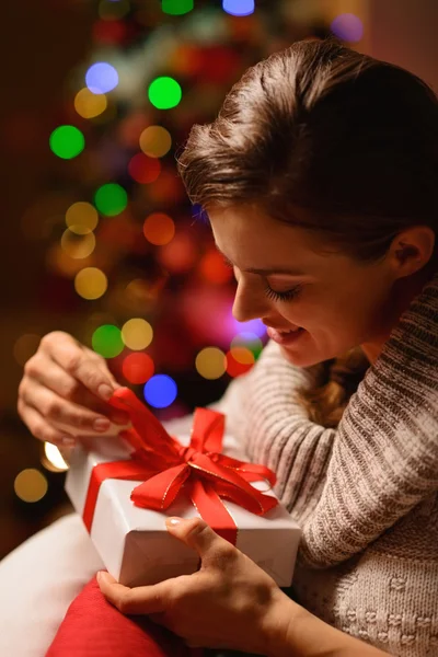 Счастливая молодая женщина сидит в кресле и открывает рождественский подарок. — стоковое фото