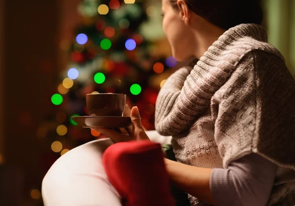 Junge Frau sitzt Stuhl mit Heißgetränk vor Weihnachten — Stockfoto